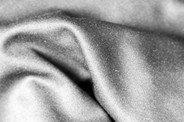 Gümüş kumaşın kırışıklıkları beyaz ışığı ve kumaşın pürüzlü dokusunu yansıtıyor..