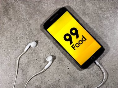 Teslimat 99 yiyecek. Üzerinde 99 yiyecek logosu olan akıllı telefon. 99 yiyecek, yemek dağıtım bölümünde bir şirkettir.