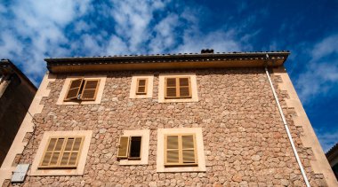 Valldemossa, Palma de Mallorca - İspanya. 26 Eylül 2022. Renkli bitkiler ve yeşil kepenklerle süslenmiş taş evleri geleneksel Majorcan mimarisinin geleneksel tadını korudu.