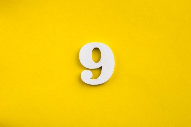 9 numara, sarı arka planda beyaz ahşap numara.