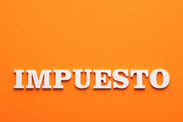 In white letters the word tax in spanish language - Orange foamy background