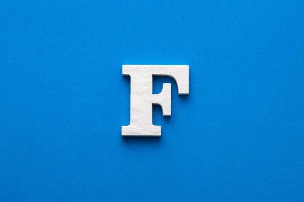 Alphabet letter F - White wooden letter on blue foamy background