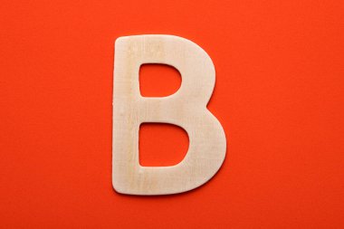 White wooden capital letter B on orange foamy background