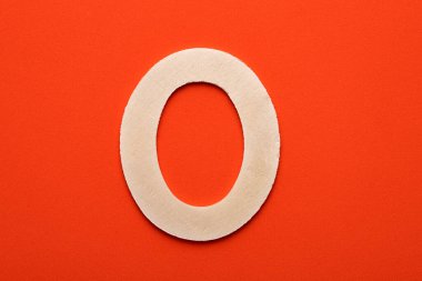 Alphabet letter O - White wood piece on orange foamy background