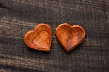 Two wooden heart shaped bowls, kitchen utensil on dark rustic background