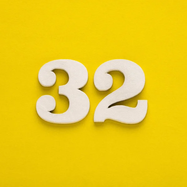 Number 32 on a yellow background - Two-digit number in white