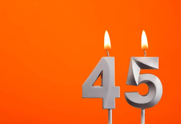Number 45 - Silver Anniversary candle on orange background