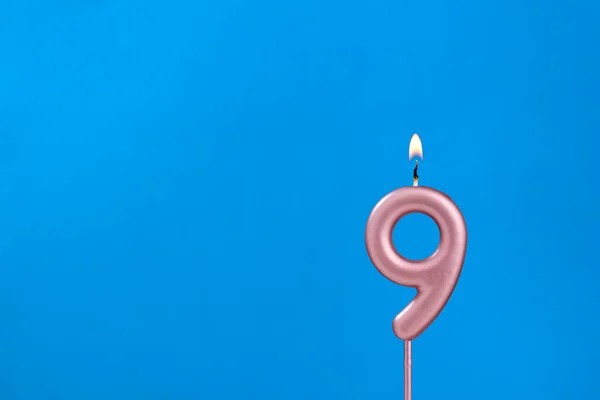 番号9 青い泡立ちの背景に燃える記念日のろうそく — ストック写真