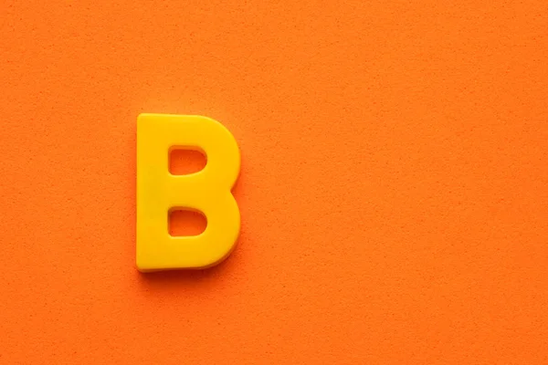 Letra Plástico Amarillo Mayúscula Sobre Fondo Espumado Naranja —  Fotos de Stock