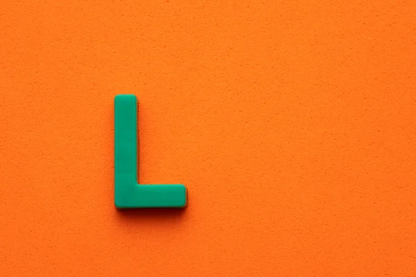 Alphabet Buchstabe Grünes Plastikstück Auf Orangefarbenem Schaumigem Hintergrund — Stockfoto
