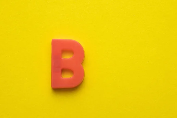 Alphabet Buchstabe Pfirsichfarbenes Plastikstück Auf Gelbem Schaumigem Hintergrund — Stockfoto