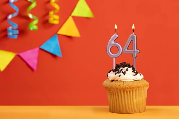 64号蜡烛的生日蛋糕 带捆扎的闪闪发光的橙色背景 — 图库照片