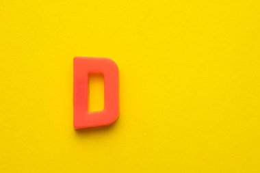 Alfabe harfi D-Şeftali renkli plastik parça sarı köpüklü arka plan