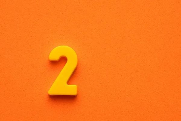Nummer Zwei Gelber Kunststoff Plastikziffer Auf Orangefarbenem Schaumhintergrund — Stockfoto