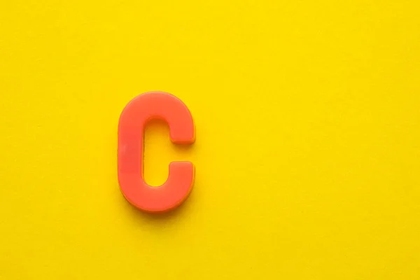 Ροδακινί Χρωματισμένο Πλαστικό Γράμμα Κεφαλαίο Κίτρινο Αφρώδες Φόντο — Φωτογραφία Αρχείου