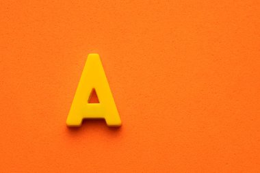 Alfabe harfi A - Turuncu köpüklü arka planda sarı plastik parça