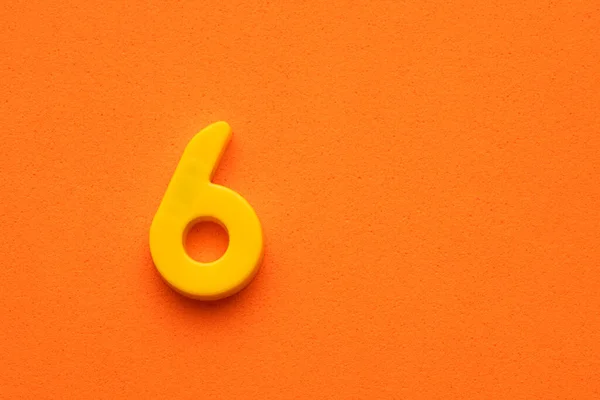 Номер Шесть Желтый Пластик Пластиковая Цифра Оранжевом Пенном Фоне — стоковое фото