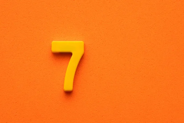 Geel Nummer Plastic Stuk Oranje Schuimige Achtergrond — Stockfoto