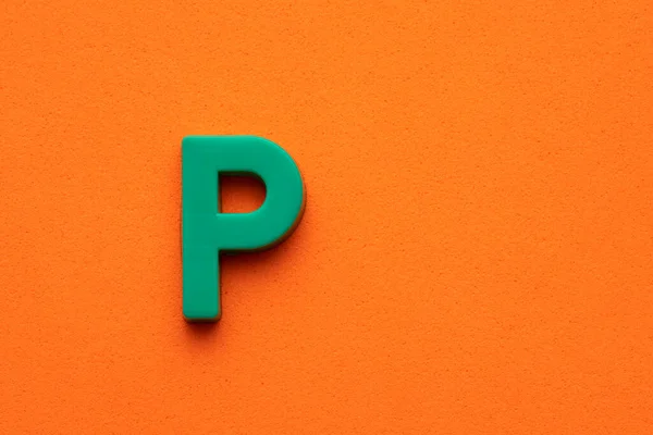字母P 橙色泡沫背景下的绿色塑料片 — 图库照片