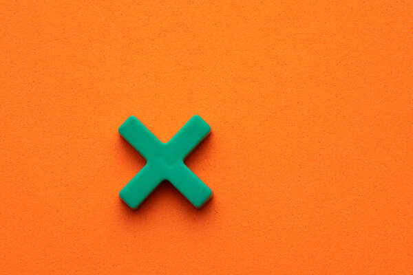 Знак умножения - зеленый пластмассовый кусок на оранжевом фоне пенопласта