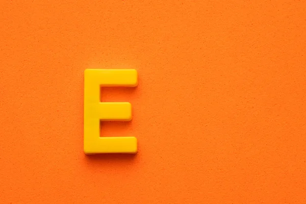 Κίτρινο Πλαστικό Γράμμα Κεφαλαίο Πορτοκαλί Αφρώδες Φόντο — Φωτογραφία Αρχείου