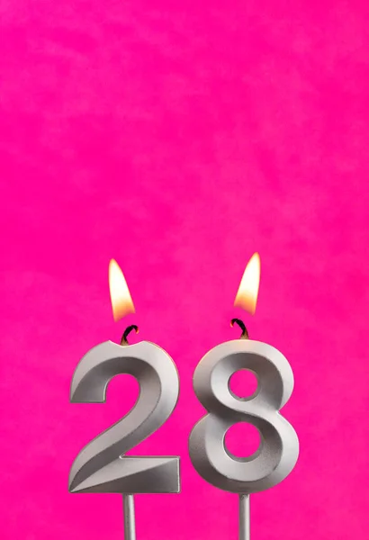 Candle 28 with flame - Silver anniversary candle on a fuchsia background