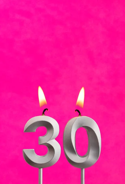 Candle 30 with flame - Silver anniversary candle on a fuchsia background