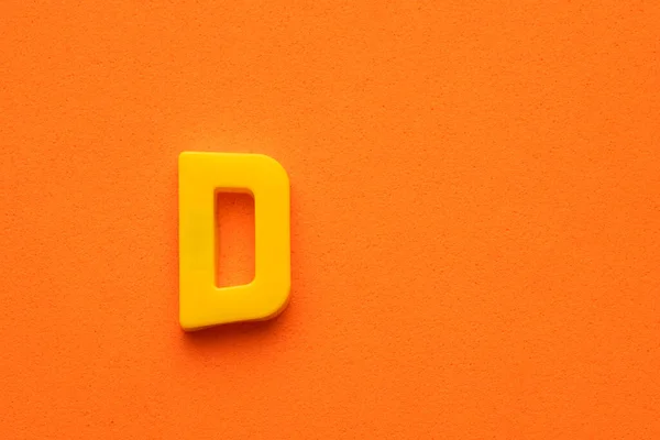 Αλφάβητο Γράμμα Κίτρινο Πλαστικό Κομμάτι Πορτοκαλί Αφρώδες Φόντο — Φωτογραφία Αρχείου
