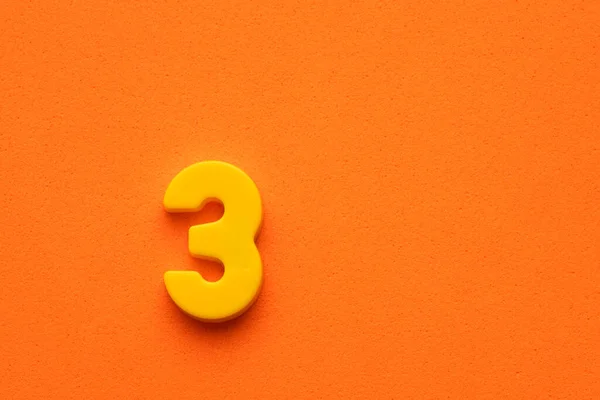 Желтое Число Кусок Пластика Оранжевом Пенном Фоне — стоковое фото