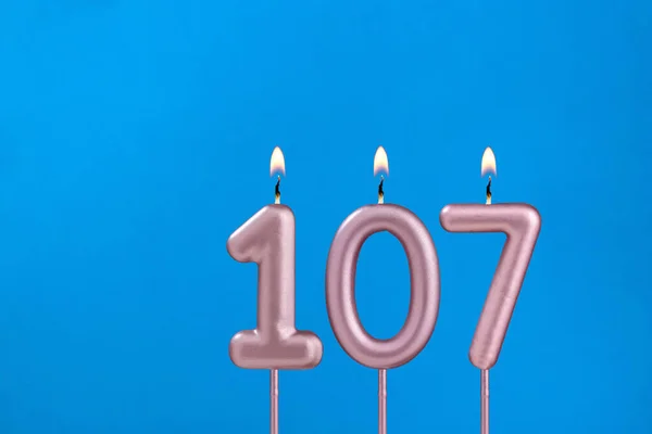 Number 107 Hořící Výročí Svíčka Modrém Pěnivém Pozadí — Stock fotografie