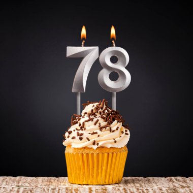 Koyu arkaplanda 78 numaralı mumla doğum günü pastası.