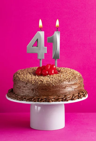 Number 41 candle - Chocolate cake on pink background