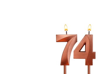 Doğum günü için beyaz arkaplanda 74 numaralı mum yanıyor.