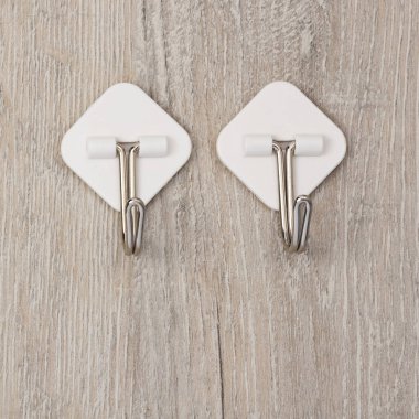 İki plastik yapıştırıcı duvarda asılı elbiseler için metal kancalarla tutturulmuş.