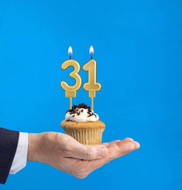 Doğum günü pastasını elden teslim ediyorum. Mavi arka planda 31 numaralı mum.