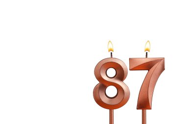 Beyaz arkaplanda 87 numaralı doğum günü mumu.