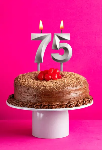 Number 75 candle - Chocolate cake on pink background