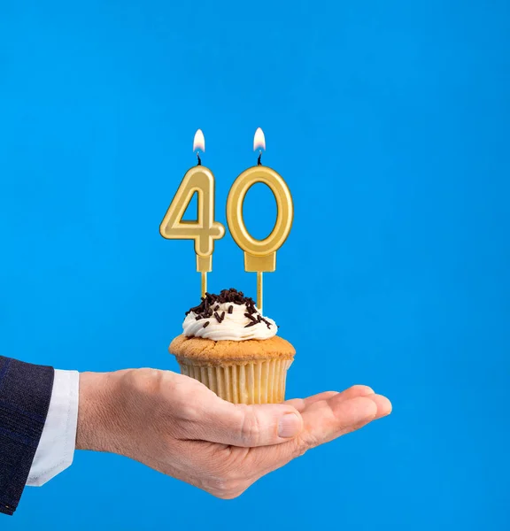 Hand delivering birthday cupcake - Candle number 40 on blue background