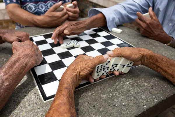 Colombian elderly people playing dominoes at the park table