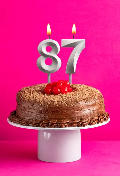 Number 87 candle - Chocolate cake on pink background