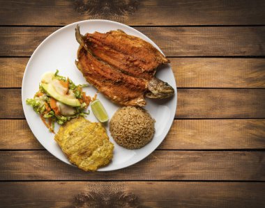 Kızarmış alabalık, hindistan cevizi pilavı, patates ve sebze salatası.