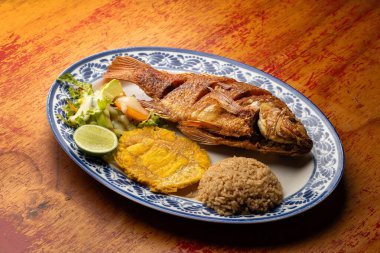 Kızarmış tilapia, yanında patacon, hindistan cevizi pilavı ve sebze salatasıyla birlikte Kolombiya yemeği.