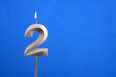 2 numaralı doğum günü - Mavi arkaplanda mum yanıyor