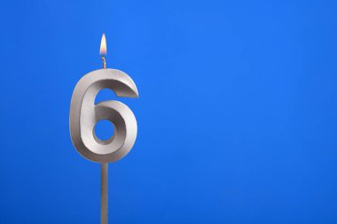 6 numaralı doğum günü - Mavi arkaplanda mum yanıyor