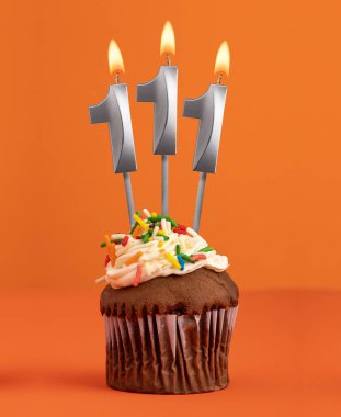 Number 111 candle - Birthday cupcake on orange background