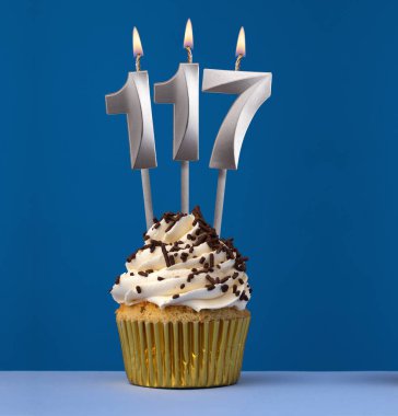 117 numaralı mumu yakmak - Mavi arka planda pastayla birlikte doğum günü kartı