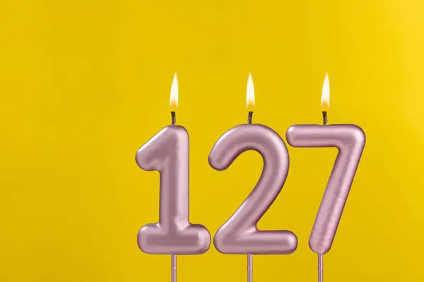 Birthday candle number 127 - Birthday celebration on yellow background