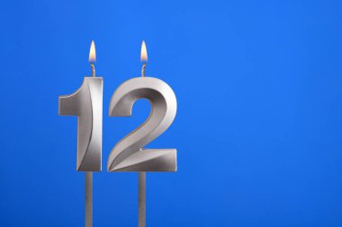 12 numaralı doğum günü - Mavi arkaplanda mum yanıyor
