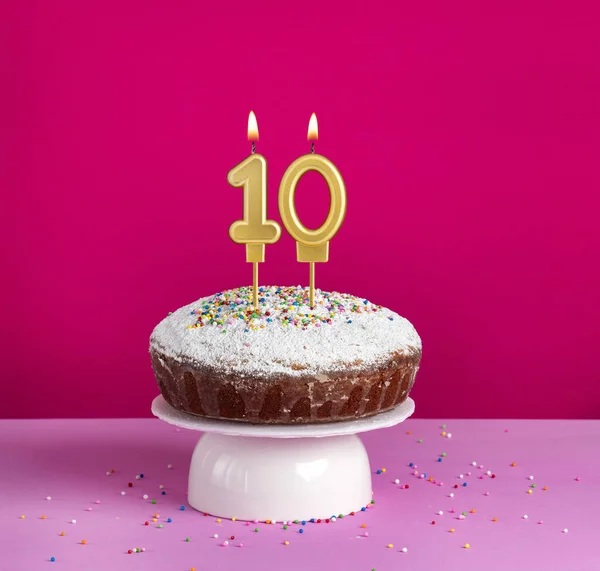 Lighted birthday candle number 10 - Birthday card on pink background
