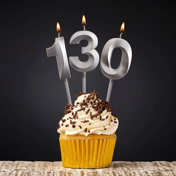 stock image birthday cupcake with number 130 candle - Celebration on dark background